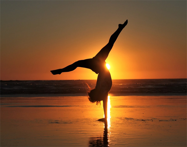 太陽の光を浴びながらヨガをする女性
